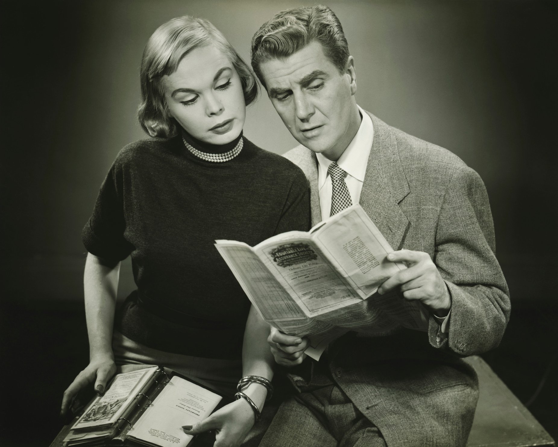 Couple reading leaflet in studio, (B&W)